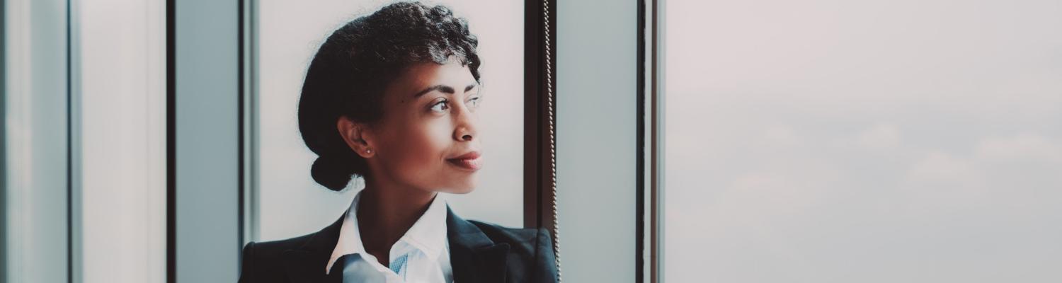Biracial woman gazes out a large office window