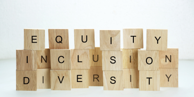 three rows of small tan blocks with with black letters are stacked atop on another and spell out Equity, Diversity, Inclusion